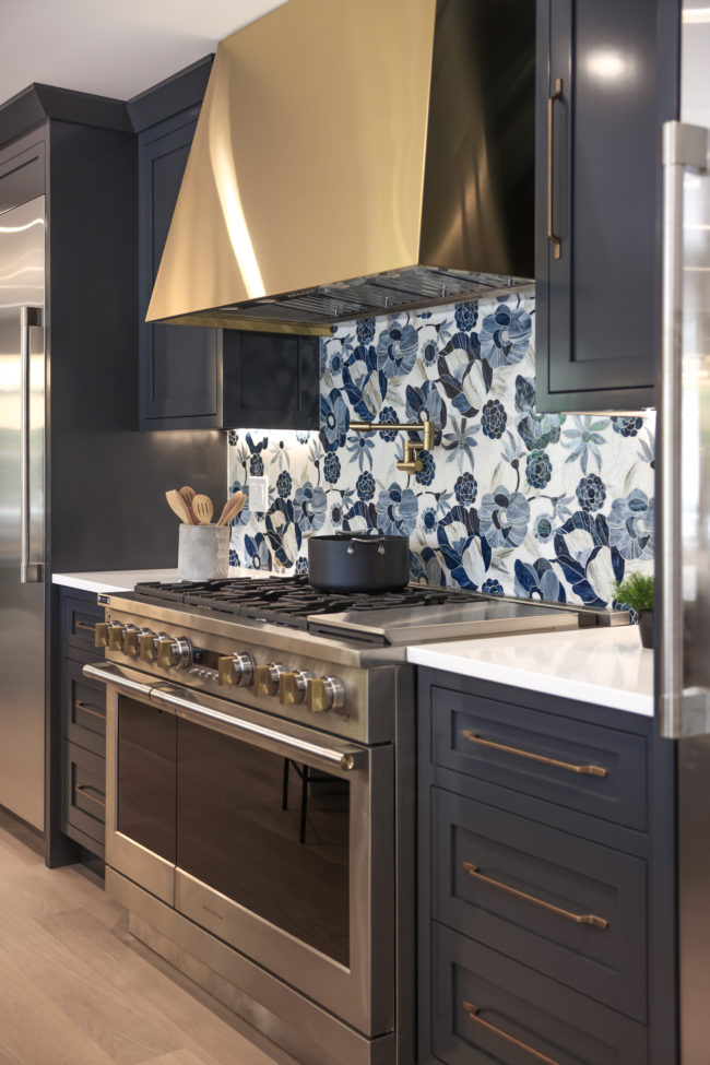 Blue floral glass kitchen backsplash with gold oven hood and pot filler