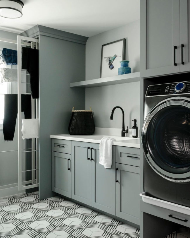laundry room with sage green cabinetry and black and white hexagon porcelain tiled floor